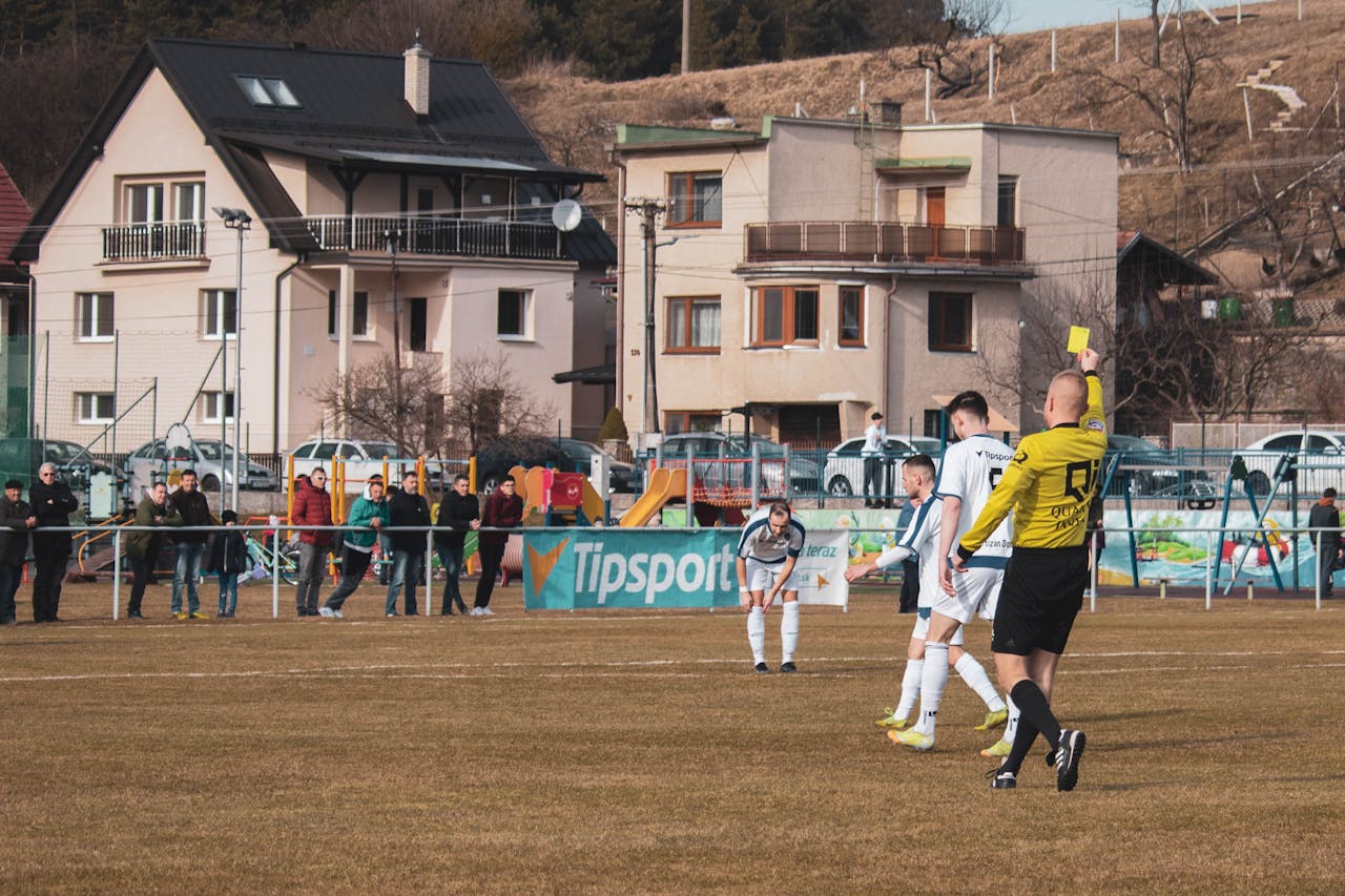 A lively soccer match in Domaniža, Slovakia, showcasing a referee giving a yellow card.